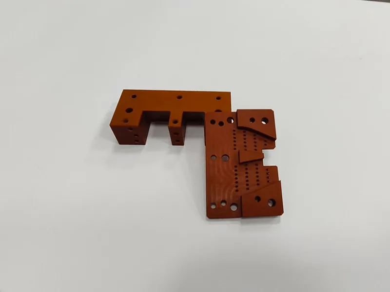 Machined laminate insulator bracket with rows of small drilled holes and stepped body